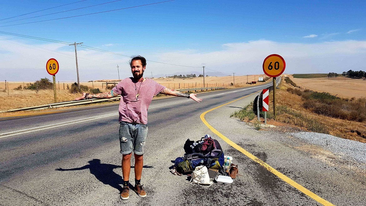 Daniel Dakuna steht am Straßenrand eines Highways in Südafrika und lacht in die Kamera.
