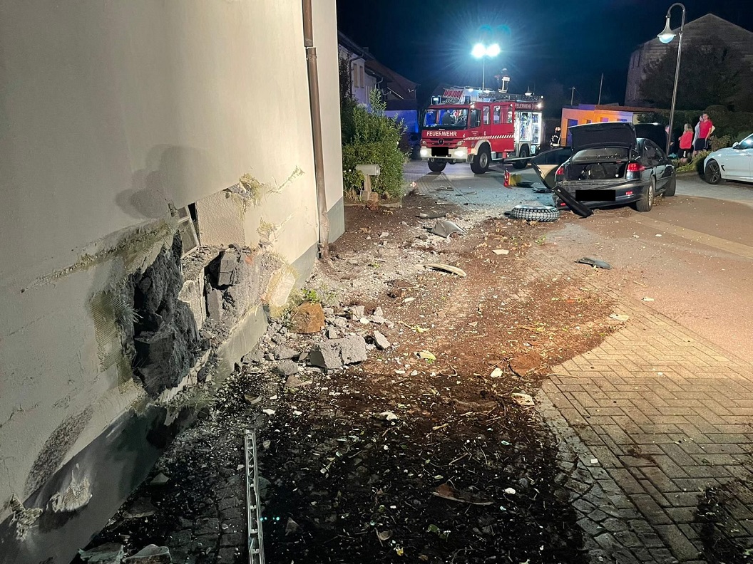 Von Auto zerstörte Hauswand, Feuerwehrauto und Unfallauto im Hintergrund