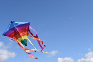 Ein regenbogenfarbener Drachen am blauen Himmel