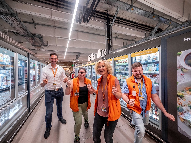 Globus Mitarbeitende freuen sich vor der Tiefkühlabteilung über ihren Gewinn