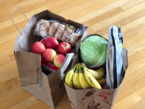 Zwei Einkaufstüten befüllt mit Lebensmitteln wie Obst und Gemüse