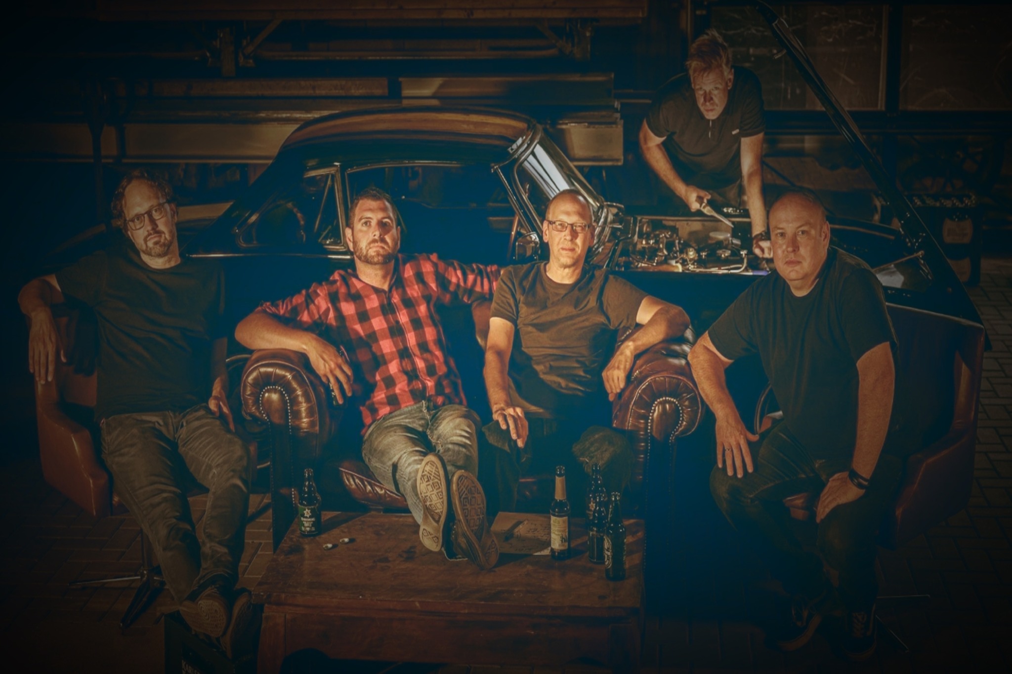 Die Musiker der Band BLOMKWIST sitzen auf einem Ledersofa vor einem Auto