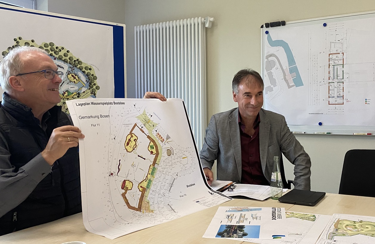 Landrat Udo Recktenwald hält einen Bauplan vor sich, neben ihm sitzt Dezernent Uwe Luther