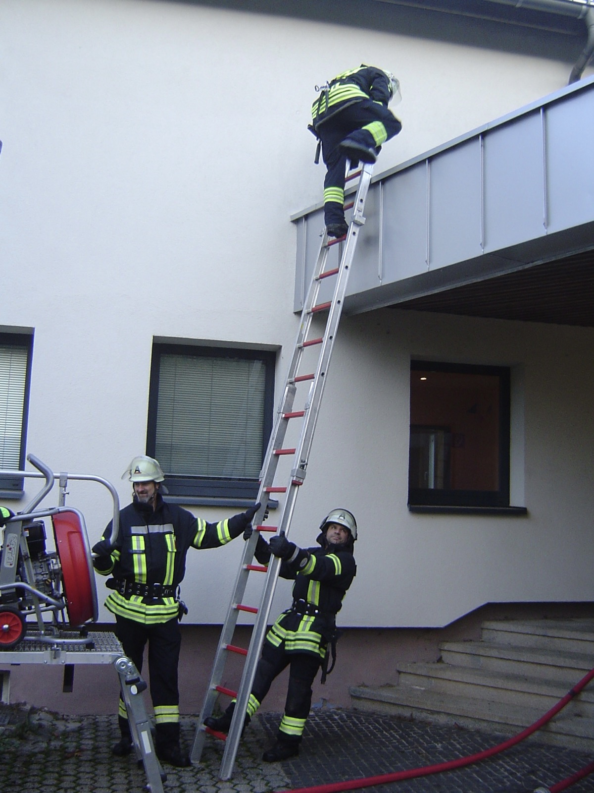 Löschbezirk Primstal bei einer Übung im Jahr 2022: Zwei Feuerwehrleute halten eine Leiter fest, während ein anderer sie hinaufsteigt.