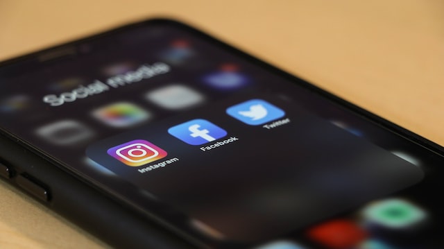Smartphone aus dem die Icons der drei Apps Instagram, Facebook und Twitter zu sehen sind.