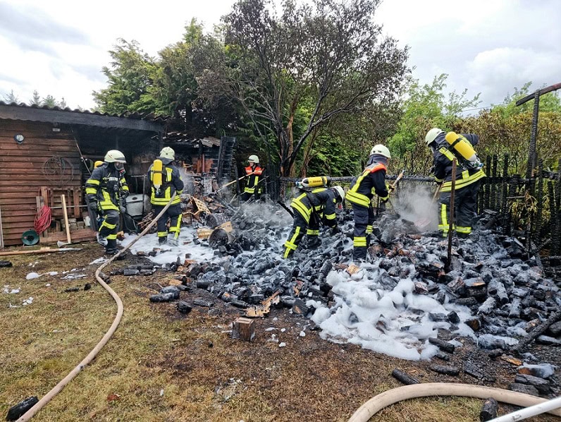 Feuerwehrleute löschen den brennenden Holzstapel