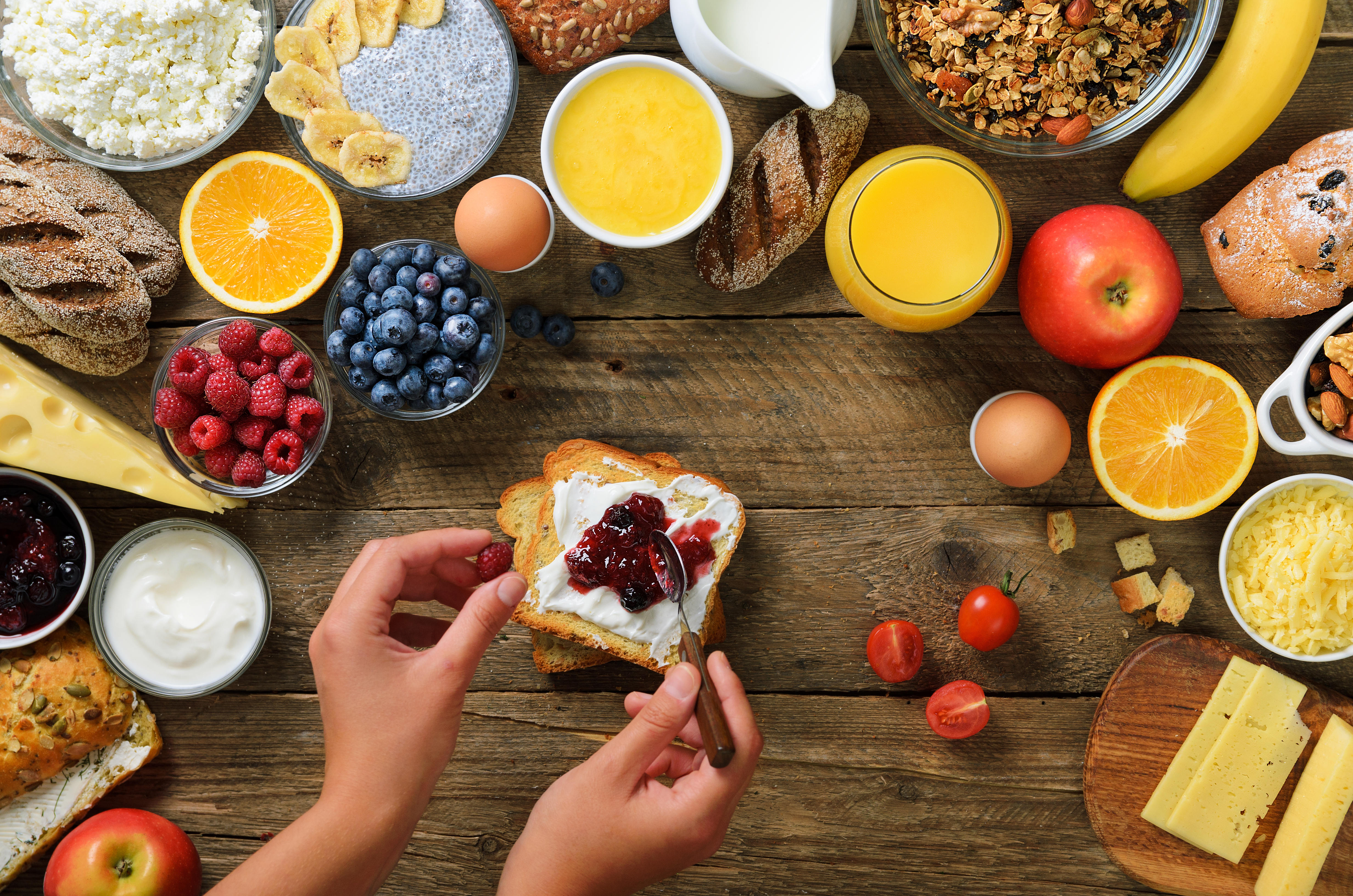 Female hands spreading butter and jam on bread. Woman cooking breakfast. Healthy breakfast