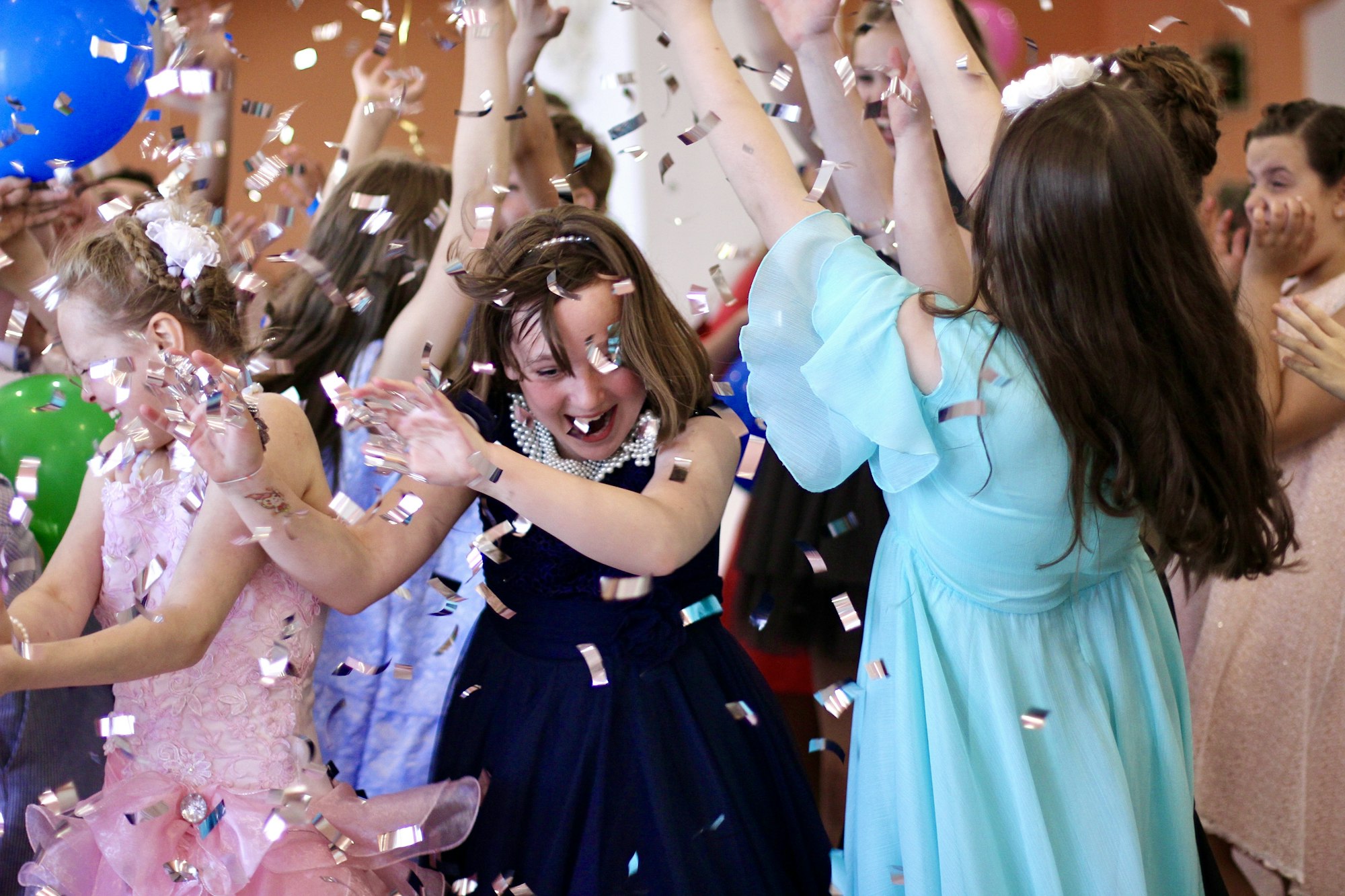 Kids having fun at a children's party in the rain of shiny confetti. Celebration, friendship.