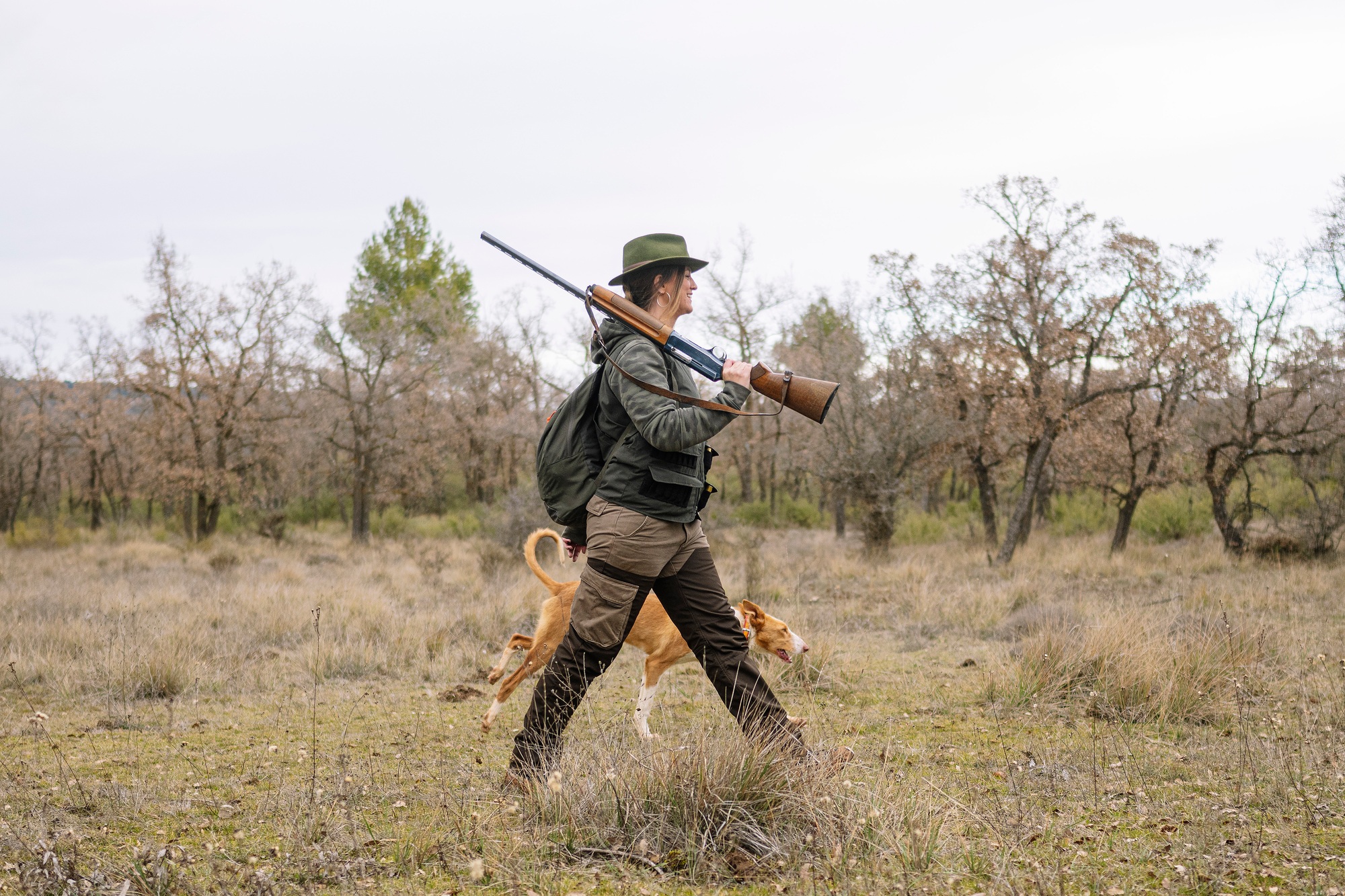 Hunter woman with shotgun hunting in the field.