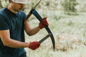 mowing grass traditional old-fashioned way with hand scythe on household village farm. young mature