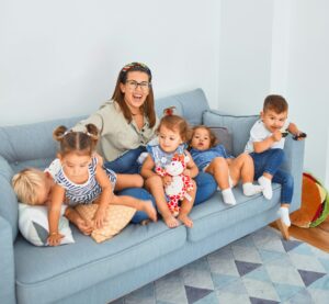 Kinderbetreuerin mit einigen Kindern spielend auf einer Couch.